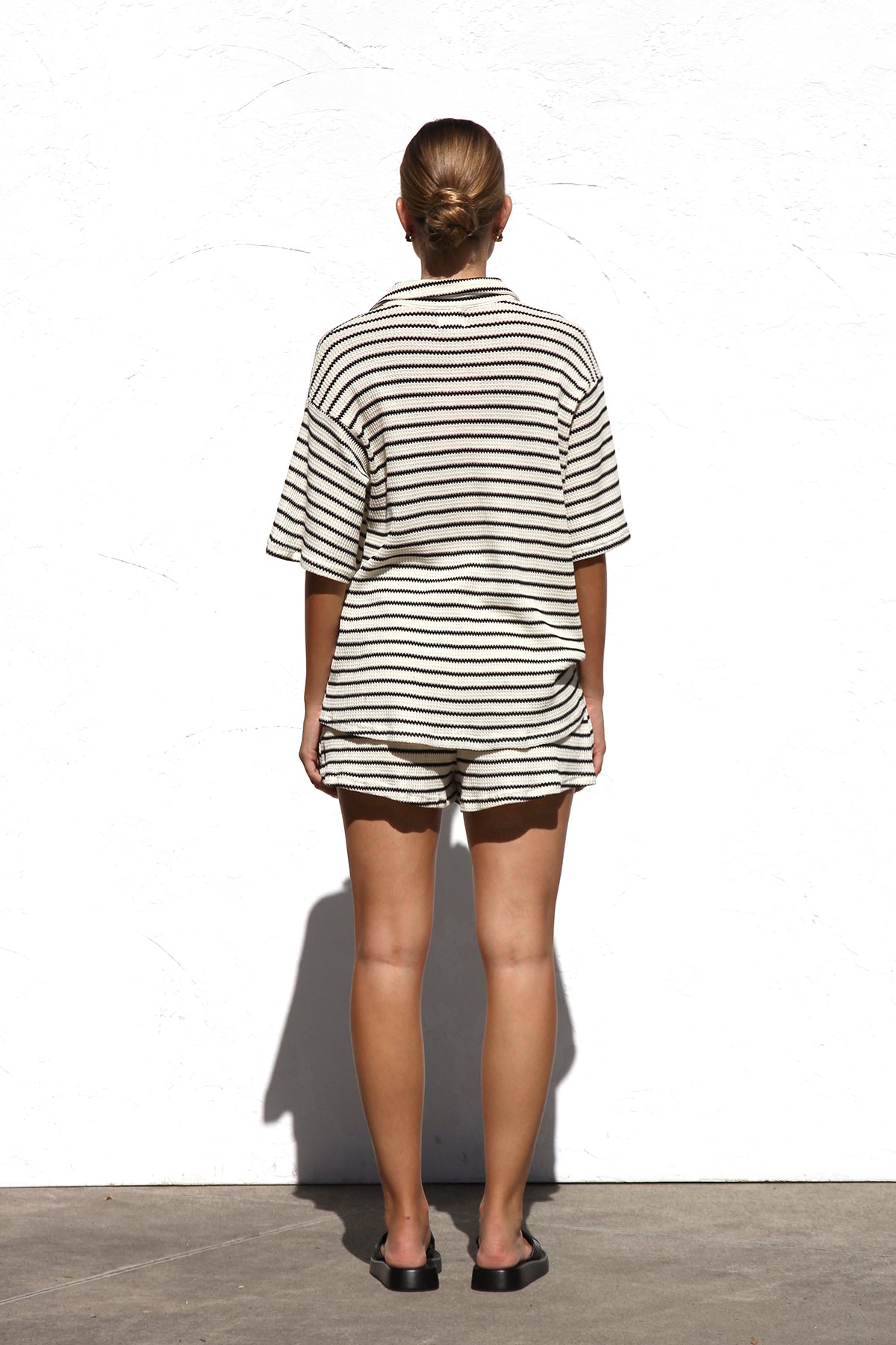 Woman in cream and black striped knit shirt and shorts set