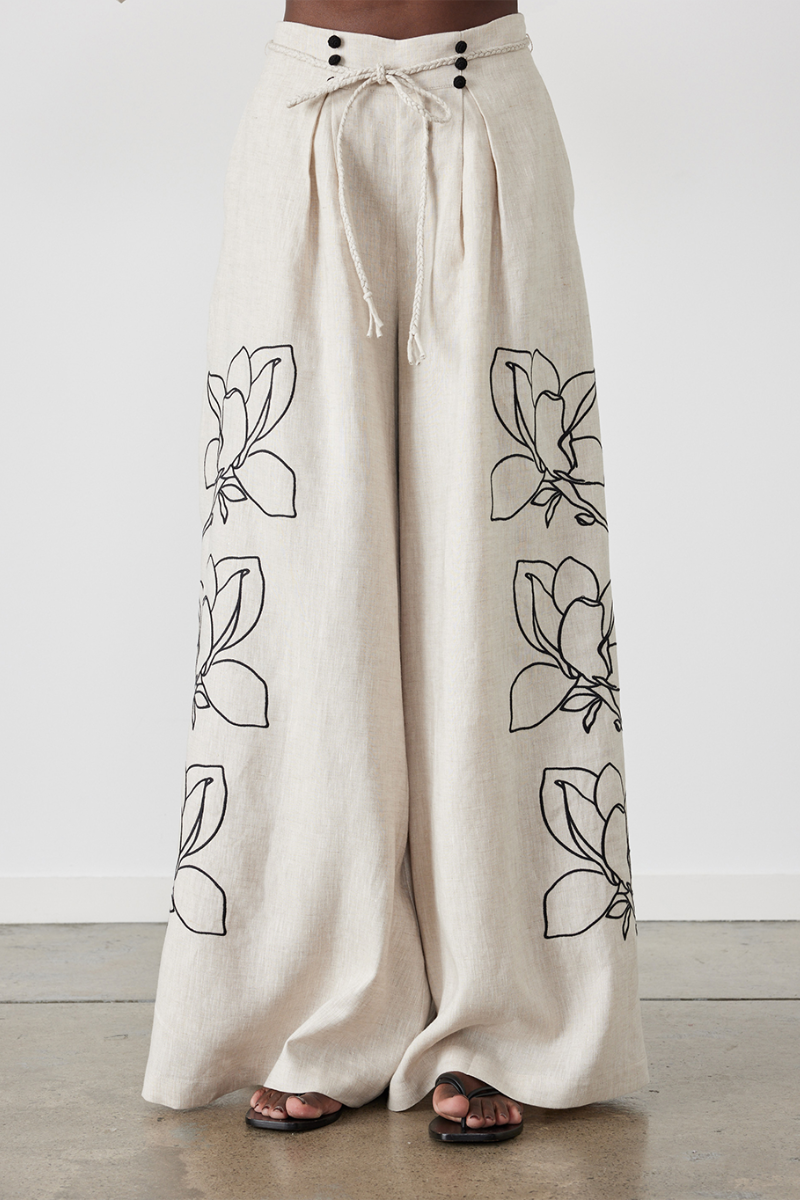 Woman wearing linen pant set with black magnolia embroidery