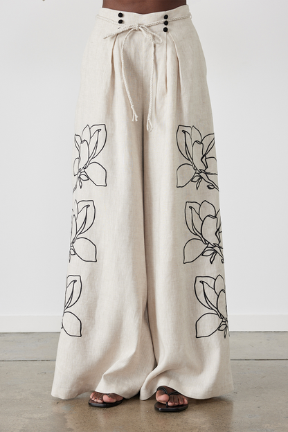 Woman wearing linen pant set with black magnolia embroidery