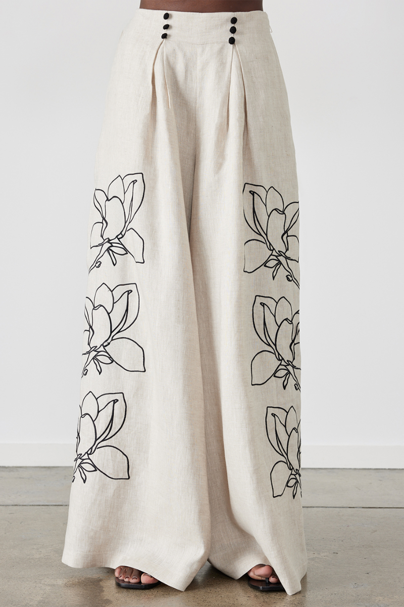 Woman wearing linen pant set with black magnolia embroidery