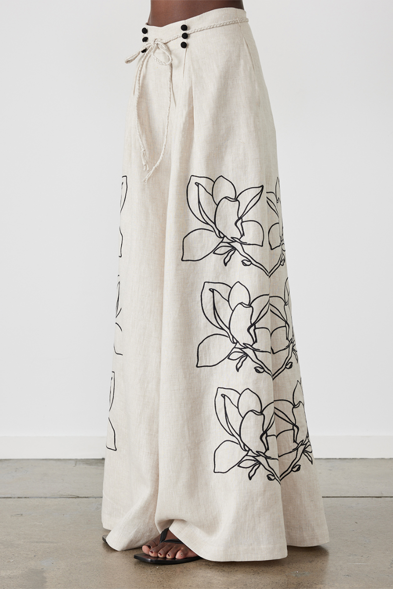 Woman wearing linen pant set with black magnolia embroidery