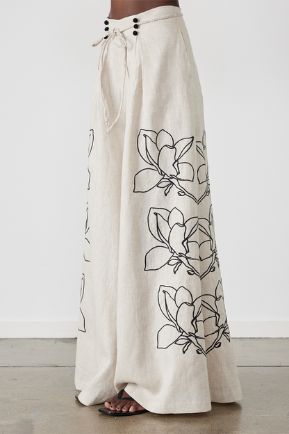 Woman wearing linen pant set with black magnolia embroidery