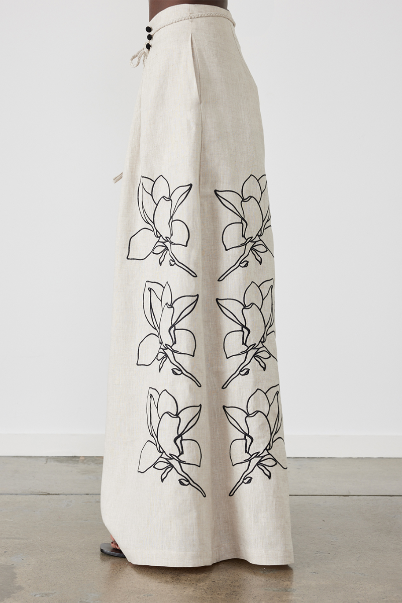 Woman wearing linen pant set with black magnolia embroidery