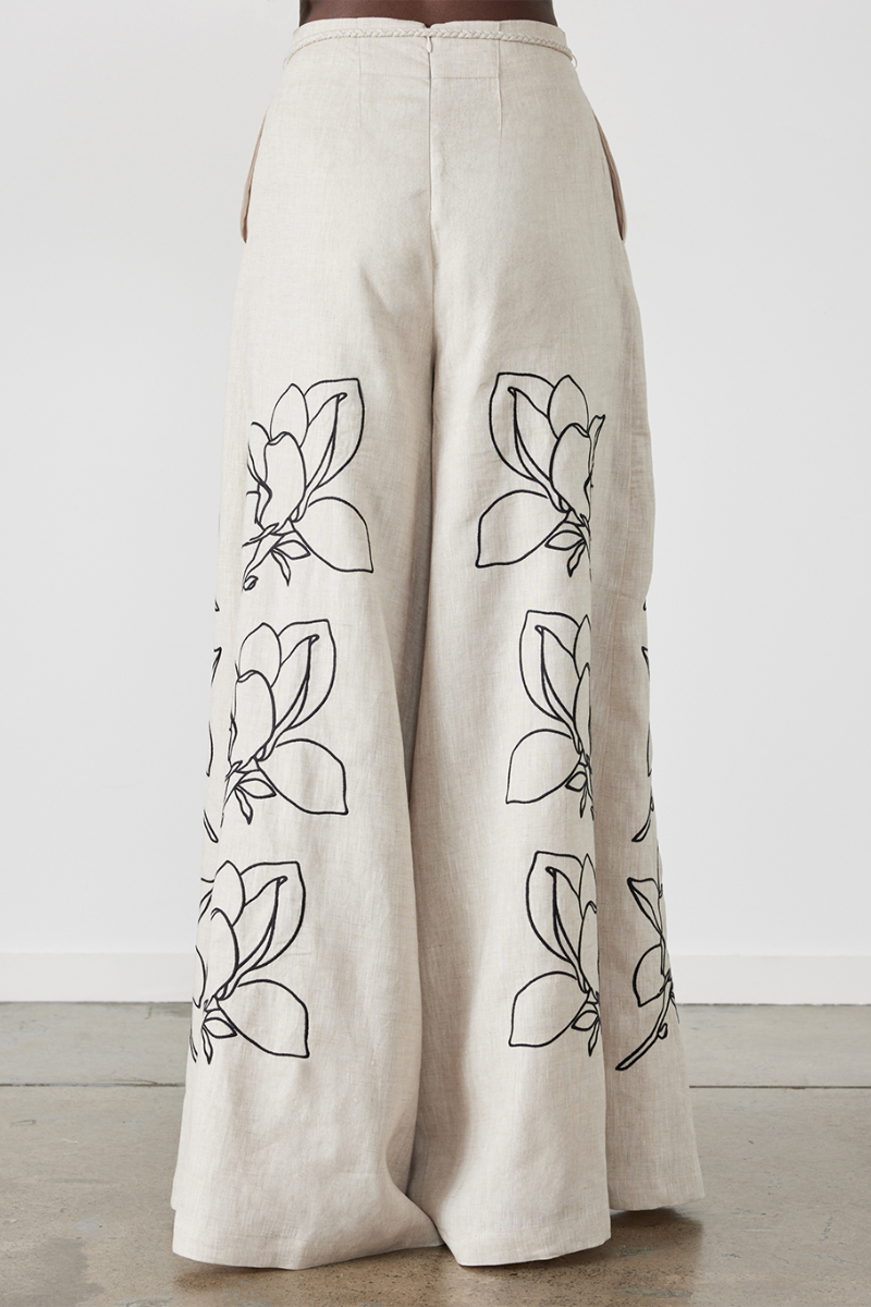 Woman wearing linen pant set with black magnolia embroidery