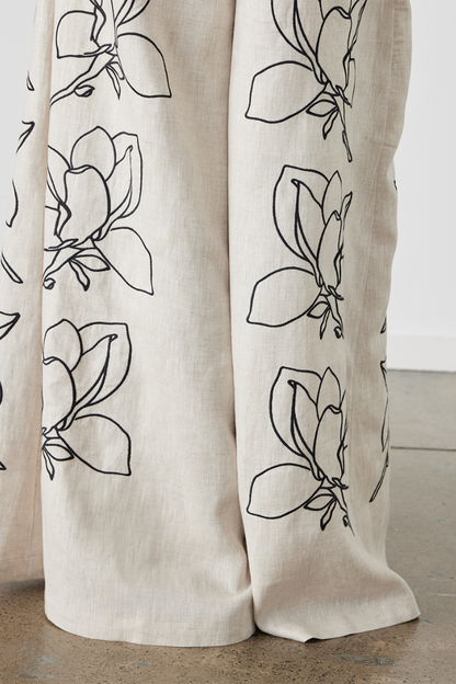 Woman wearing linen pant set with black magnolia embroidery