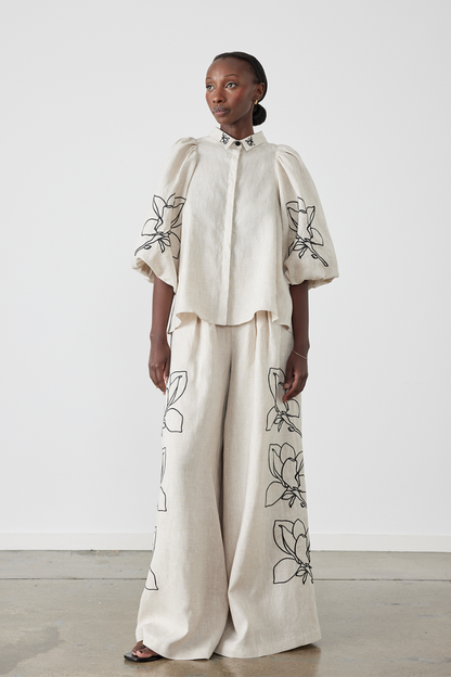 Woman wearing linen pant set with black magnolia embroidery