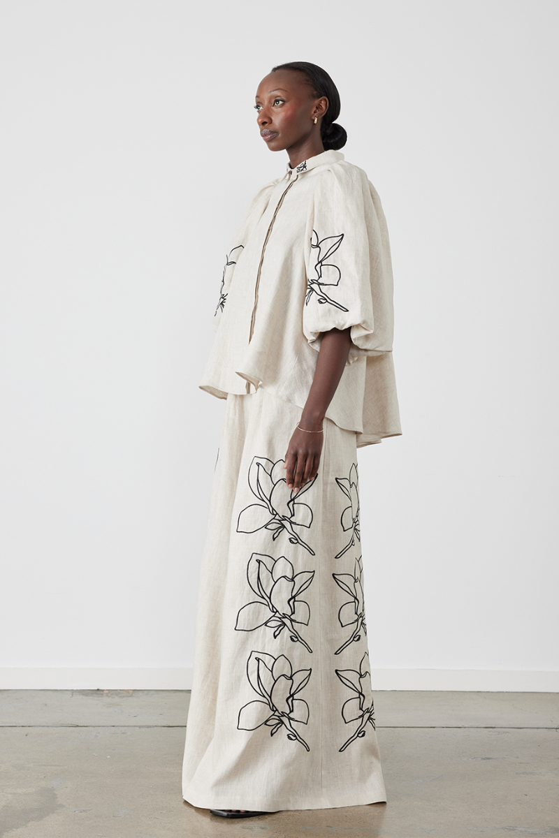 Woman wearing linen pant set with black magnolia embroidery
