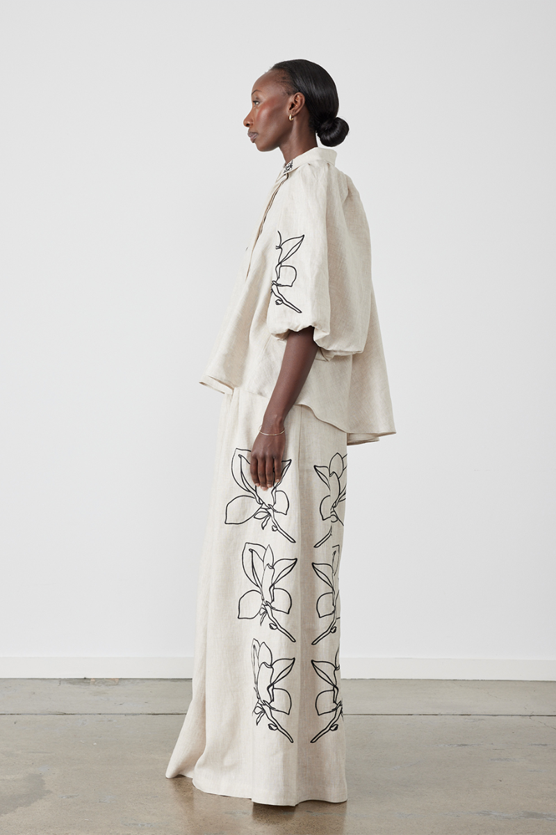 Woman wearing linen pant set with black magnolia embroidery