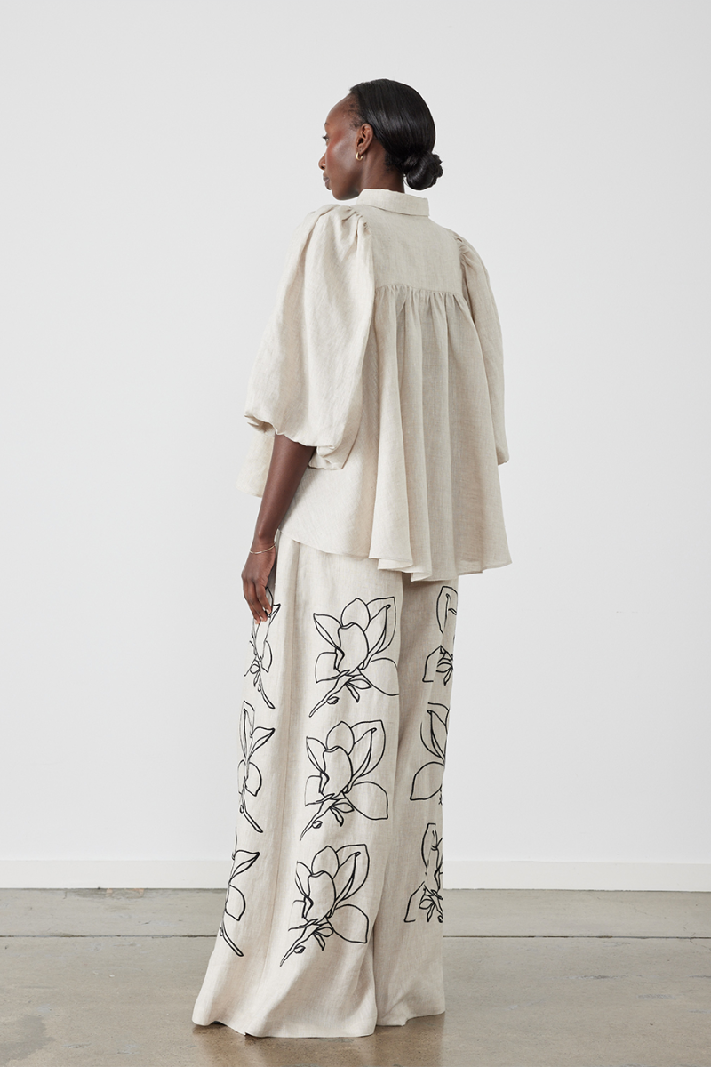 Woman wearing linen pant set with black magnolia embroidery