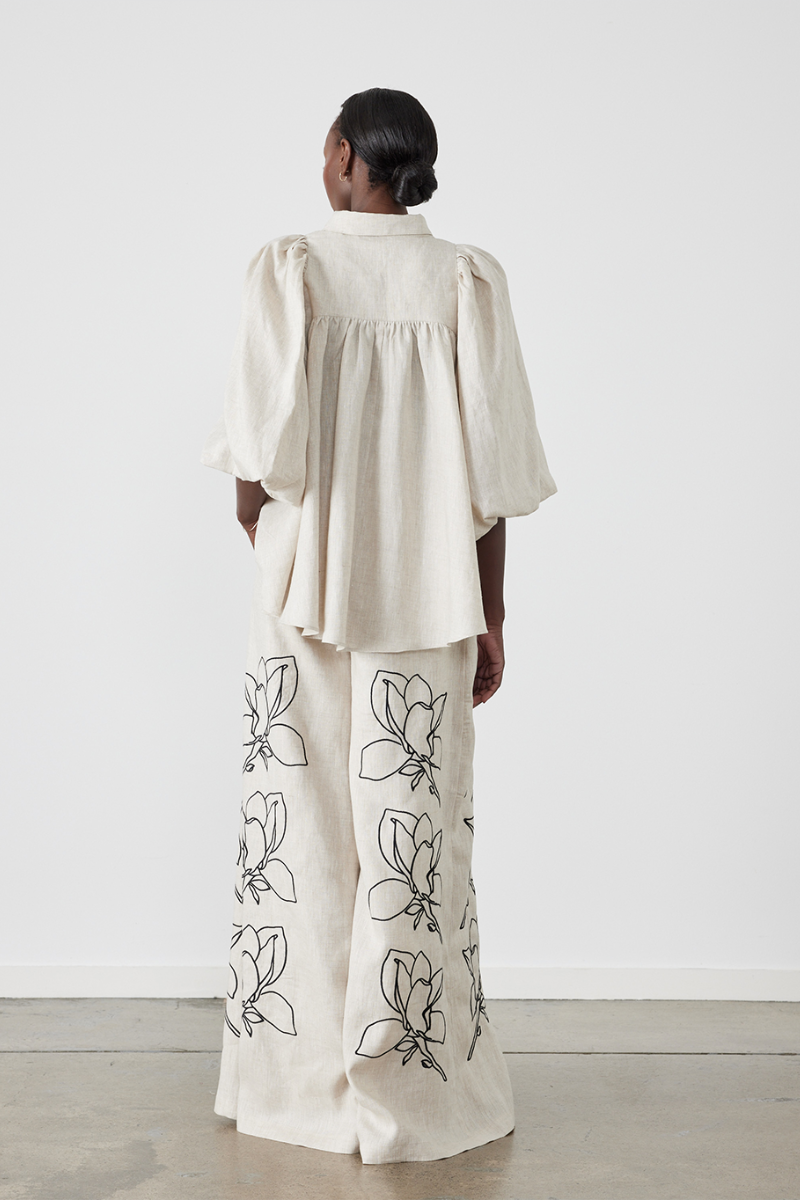 Woman wearing linen pant set with black magnolia embroidery