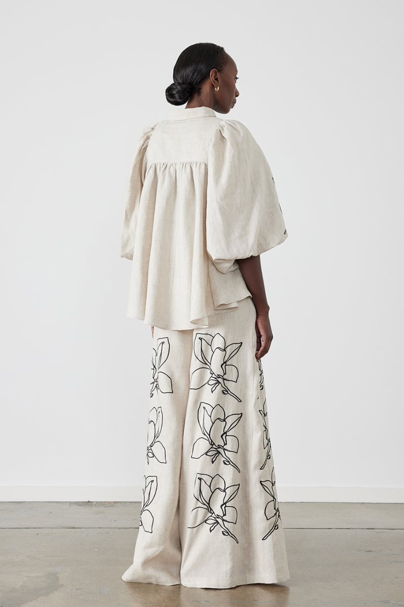 Woman wearing linen pant set with black magnolia embroidery