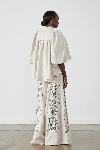 Woman wearing linen pant set with black magnolia embroidery