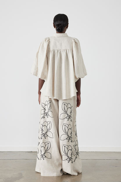 Woman wearing linen pant set with black magnolia embroidery