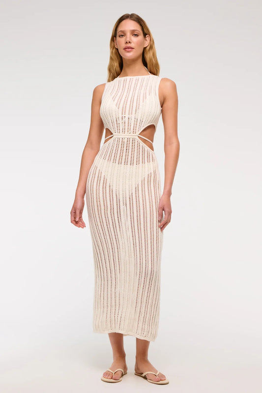 Woman wearing a long, off-white crochet knit dress with waist cutouts.