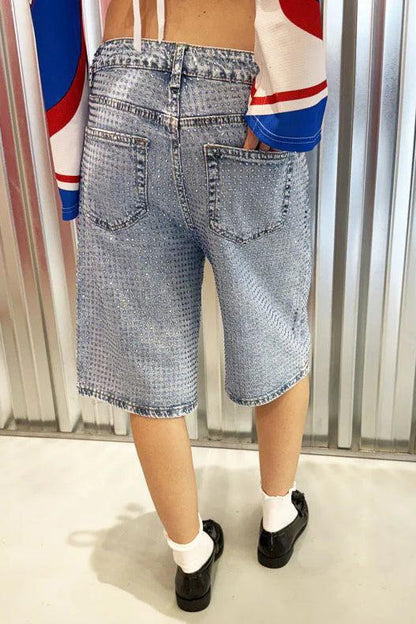 Woman wearing light wash denim bermuda shorts with sparkly embellishments