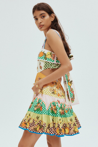 Woman in colorful citrus print mini dress holding fishing rod