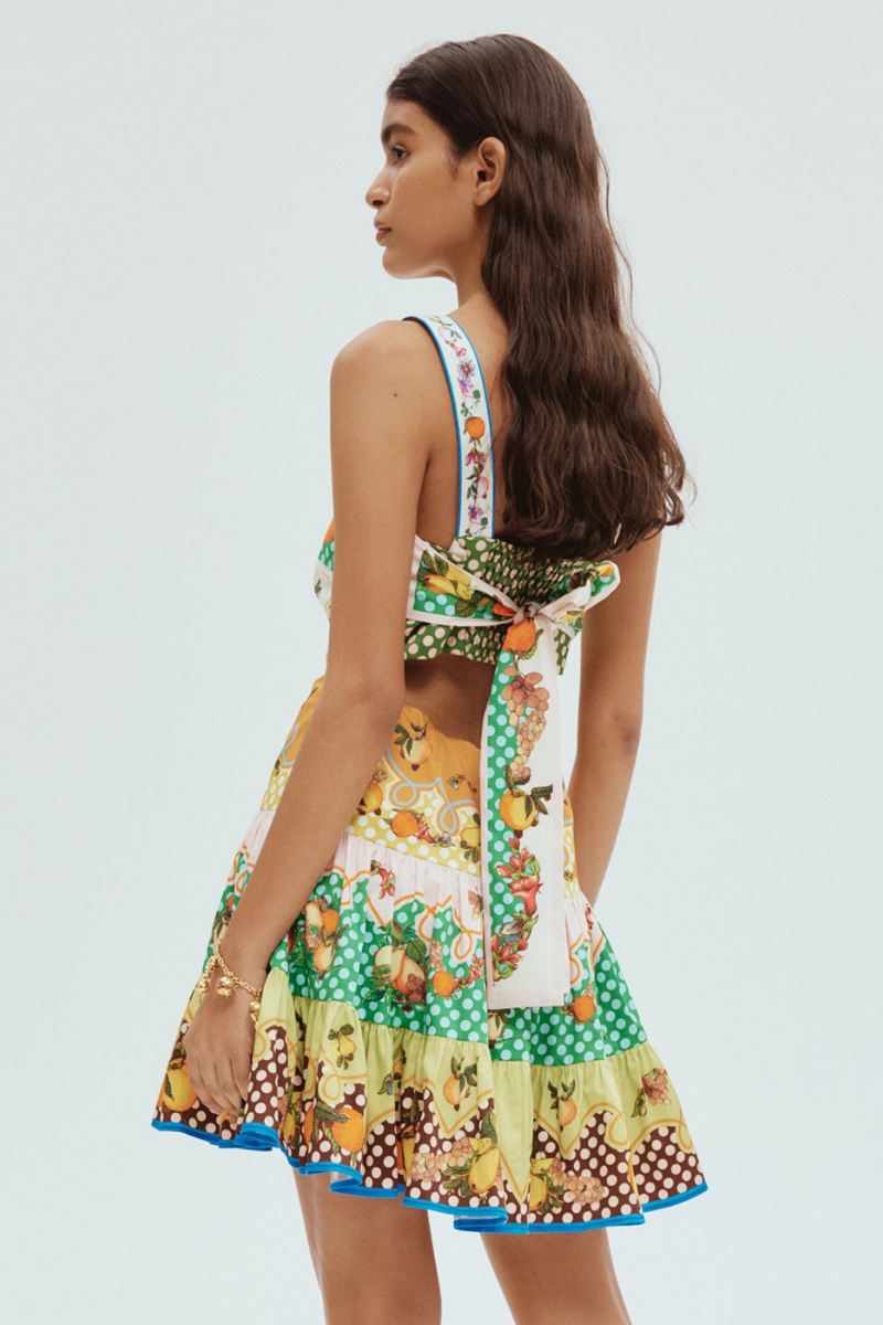 Woman in colorful citrus print mini dress holding fishing rod