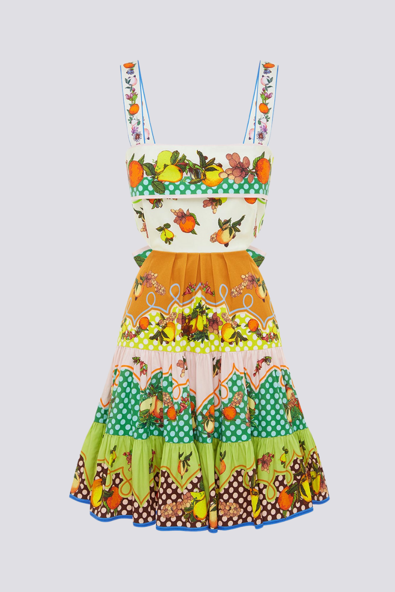 Woman in colorful citrus print mini dress holding fishing rod