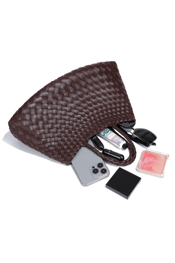 Woman holding brown woven tote bag