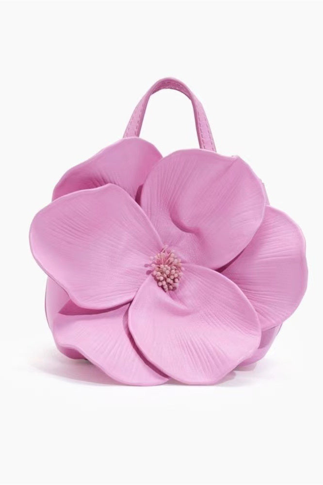 Woman in pink floral chiffon dress holding a red flower-shaped purse