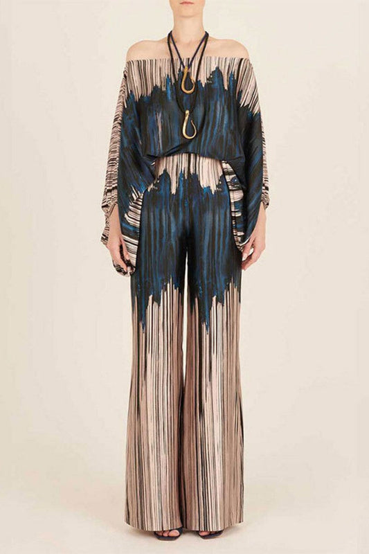 Woman wearing off-shoulder blue and beige abstract print silk jumpsuit