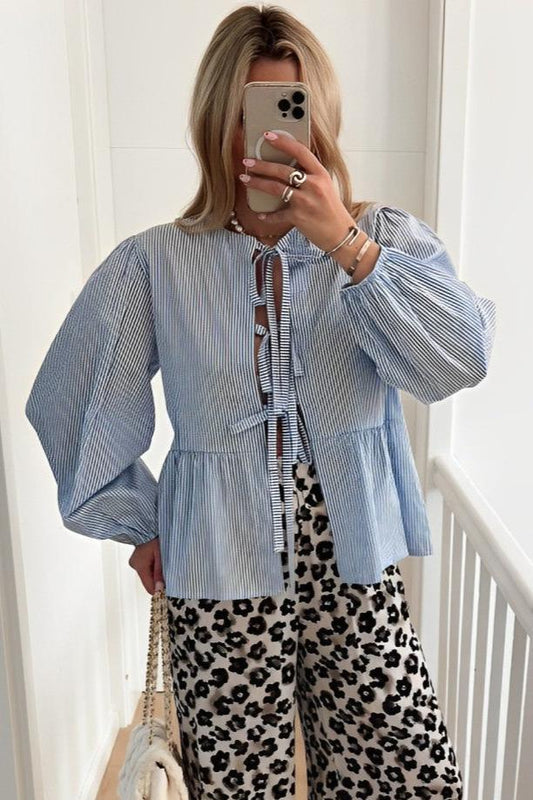 Woman in blue and white striped tie-neck blouse