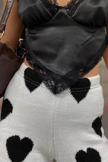 Woman wearing white ribbed knit pants with black heart print