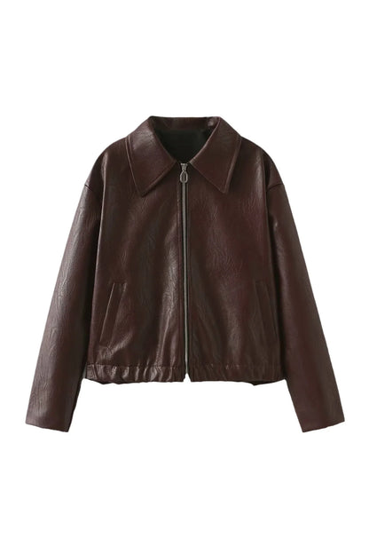 Woman in burgundy faux leather bomber jacket and black jeans.