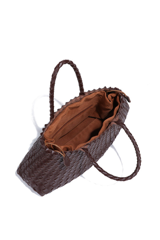 Woman holding brown woven tote bag