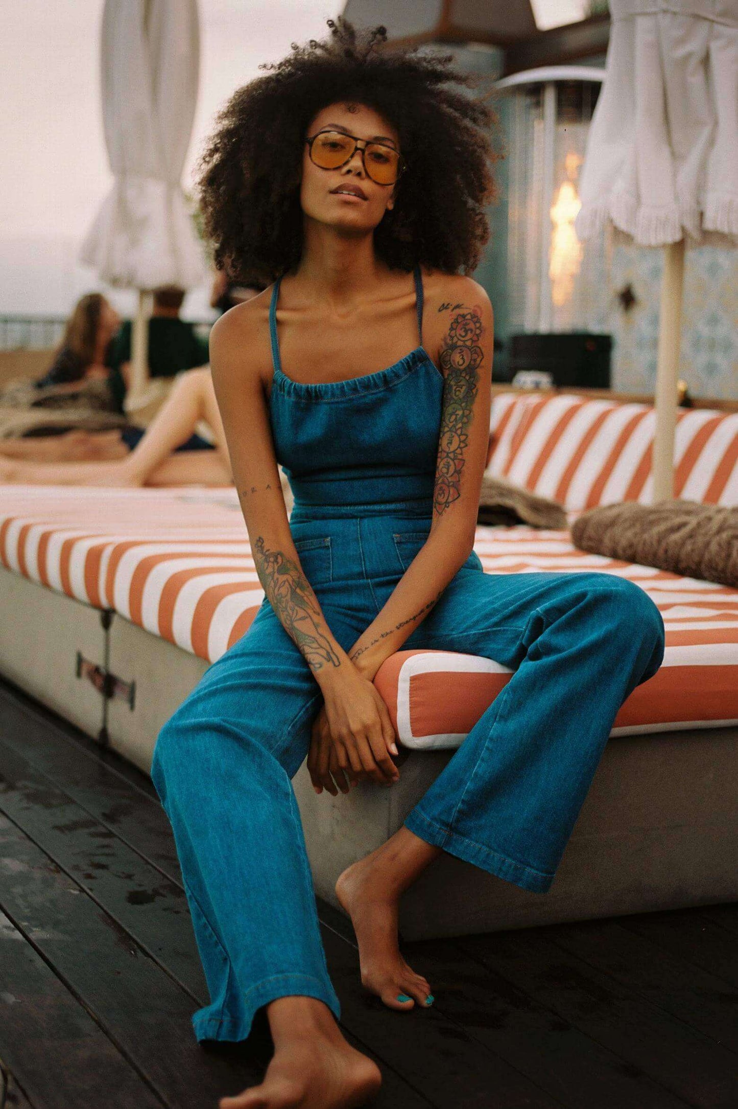 Woman in a blue denim jumpsuit with a halter neck and wide legs.
