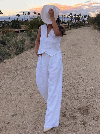Woman in white linen vest and wide-leg pants on stone steps.