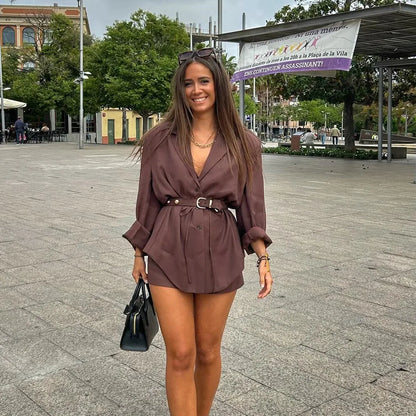Woman in brown satin blazer dress with belt and black handbag