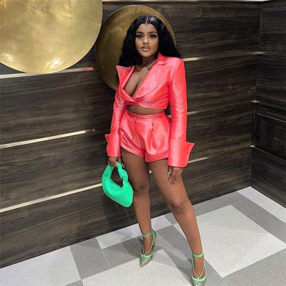 Woman in coral satin blazer and shorts set posing outdoors