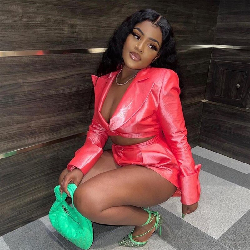 Woman in coral satin blazer and shorts set posing outdoors