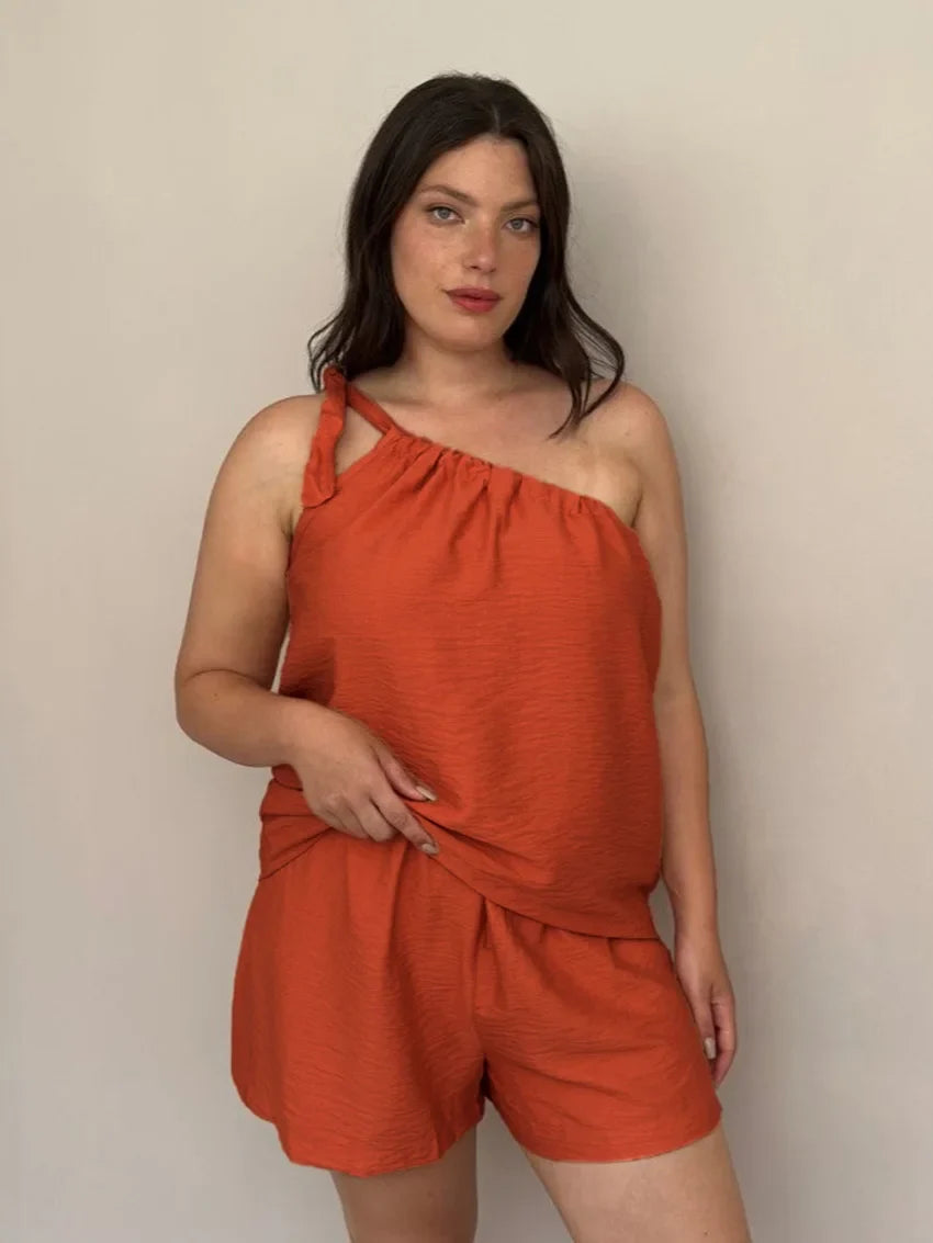 Woman wearing a rust-colored one-shoulder top and shorts set