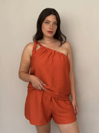 Woman wearing a rust-colored one-shoulder top and shorts set