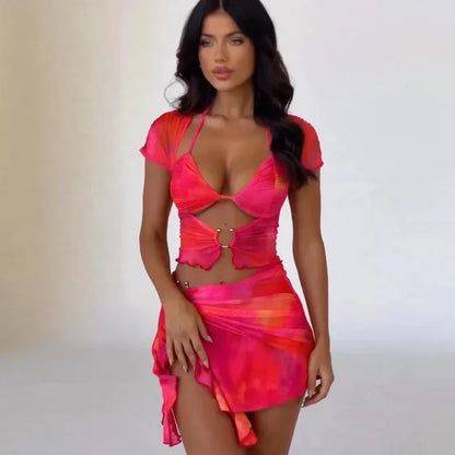 Woman in pink and orange mesh halter top and skirt set.