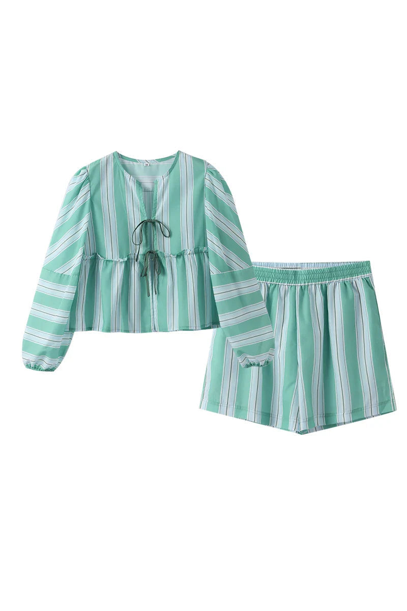 Woman in striped green cotton shorts set holding a drink.