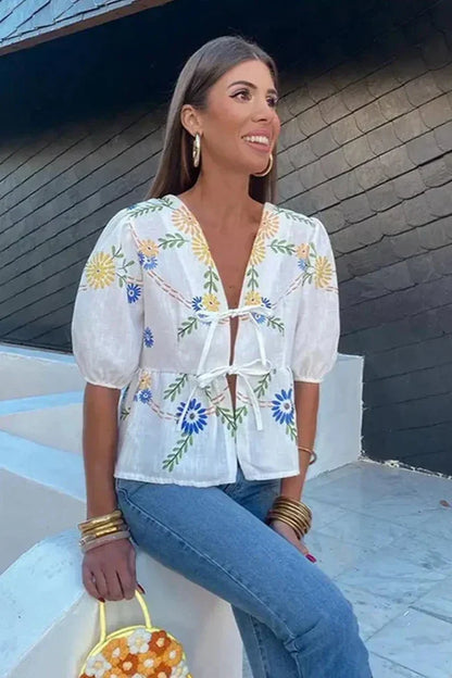 Woman in white linen blouse with blue and yellow floral embroidery
