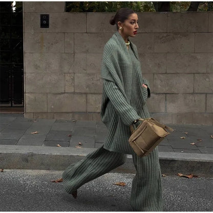 Woman in burgundy ribbed knit sweater and wide leg pants carrying a brown suede bag.
