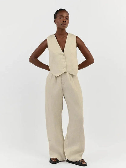 Woman in white linen vest and wide-leg pants on stone steps.