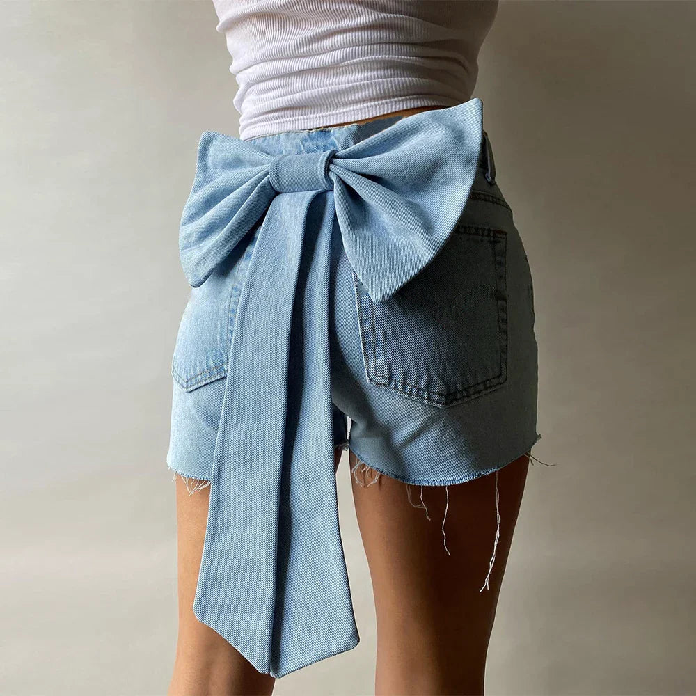 Back view of light wash denim shorts with large bow detail