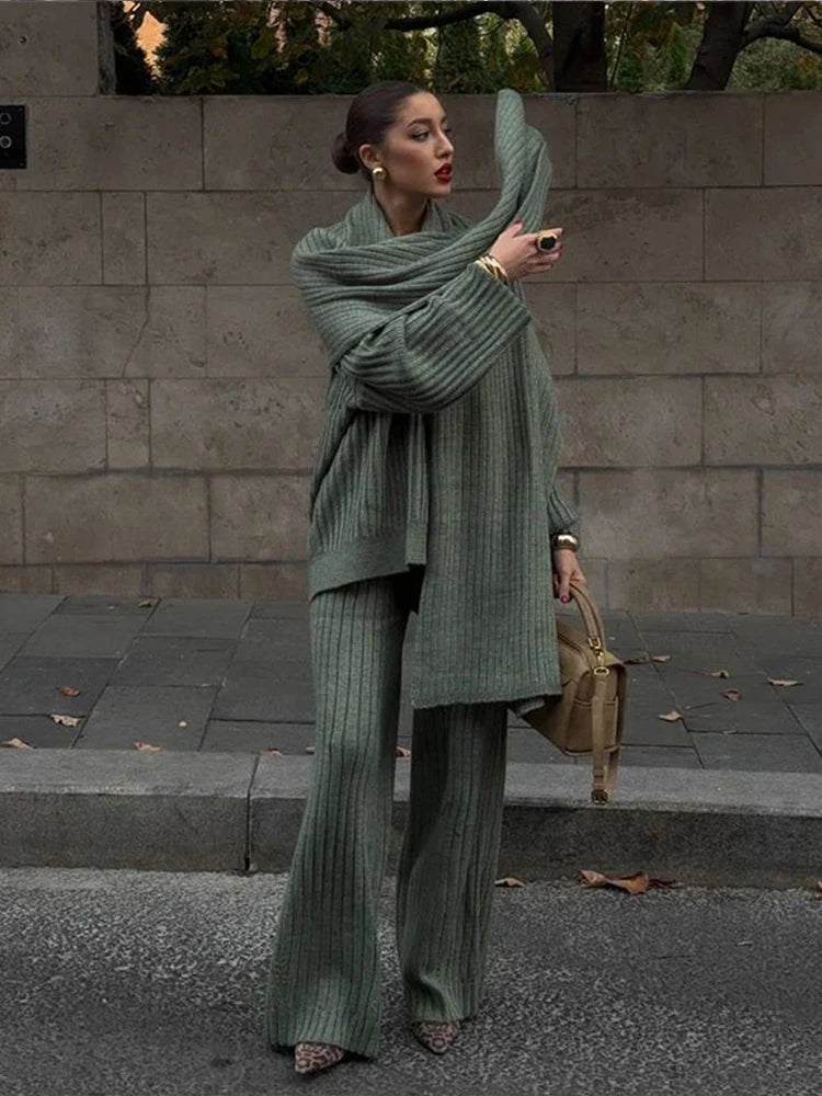 Woman in burgundy ribbed knit sweater and wide leg pants carrying a brown suede bag.