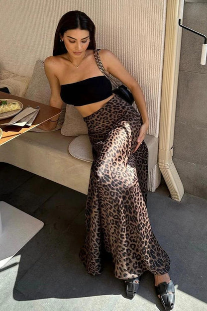 Woman wearing a black tube top and a leopard print satin maxi skirt.