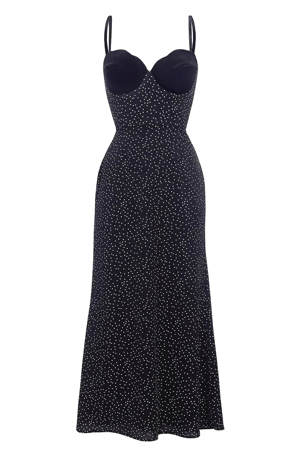 Woman in black polka dot midi dress with velvet bodice leaning against white wall