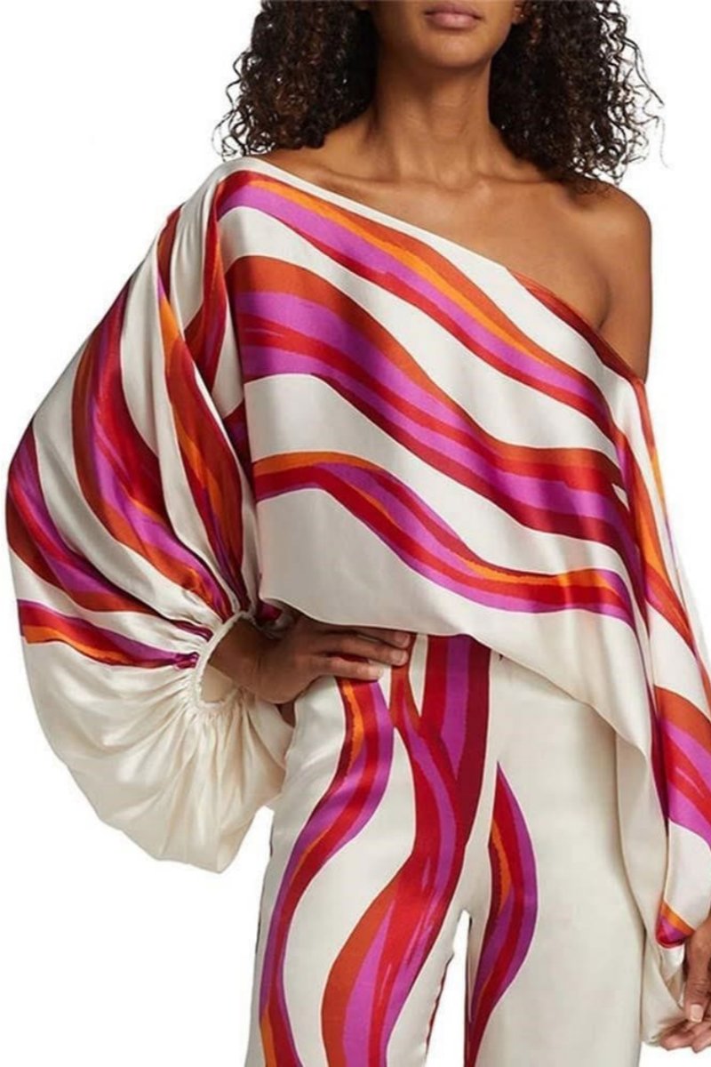 Woman in ivory satin pant set with pink and orange wave print