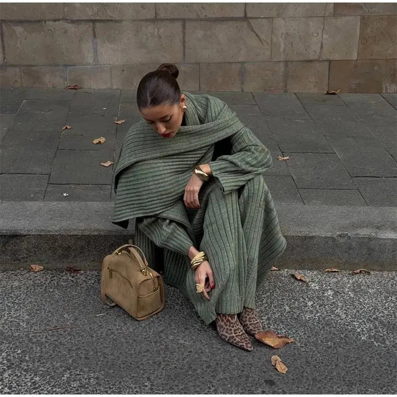 Woman in burgundy ribbed knit sweater and wide leg pants carrying a brown suede bag.