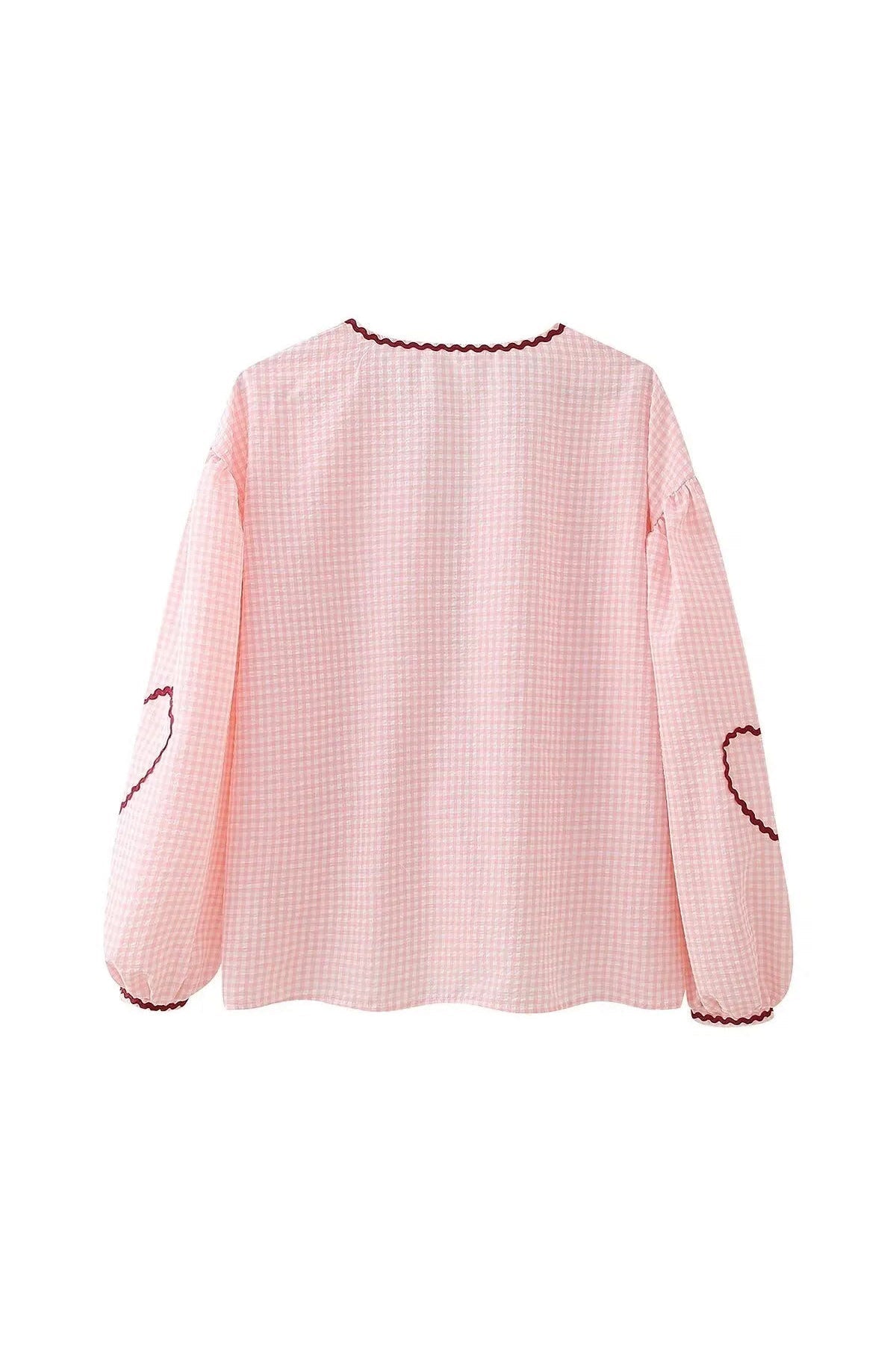 Woman in pink gingham blouse with heart pockets and denim shorts