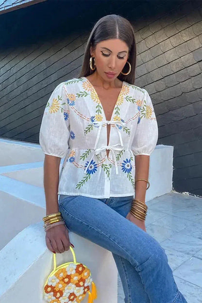 Woman in white linen blouse with blue and yellow floral embroidery