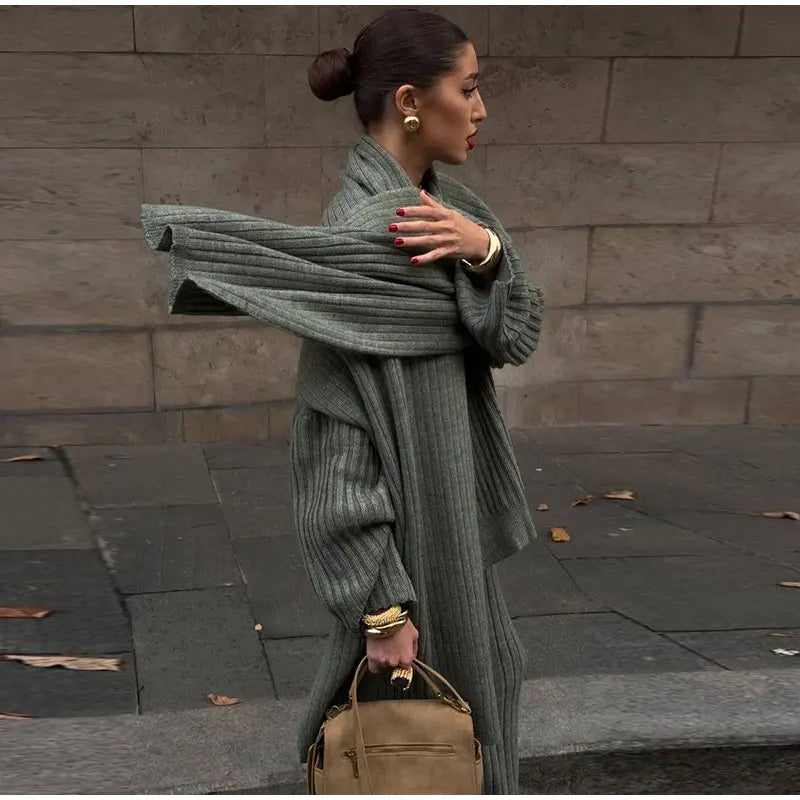 Woman in burgundy ribbed knit sweater and wide leg pants carrying a brown suede bag.